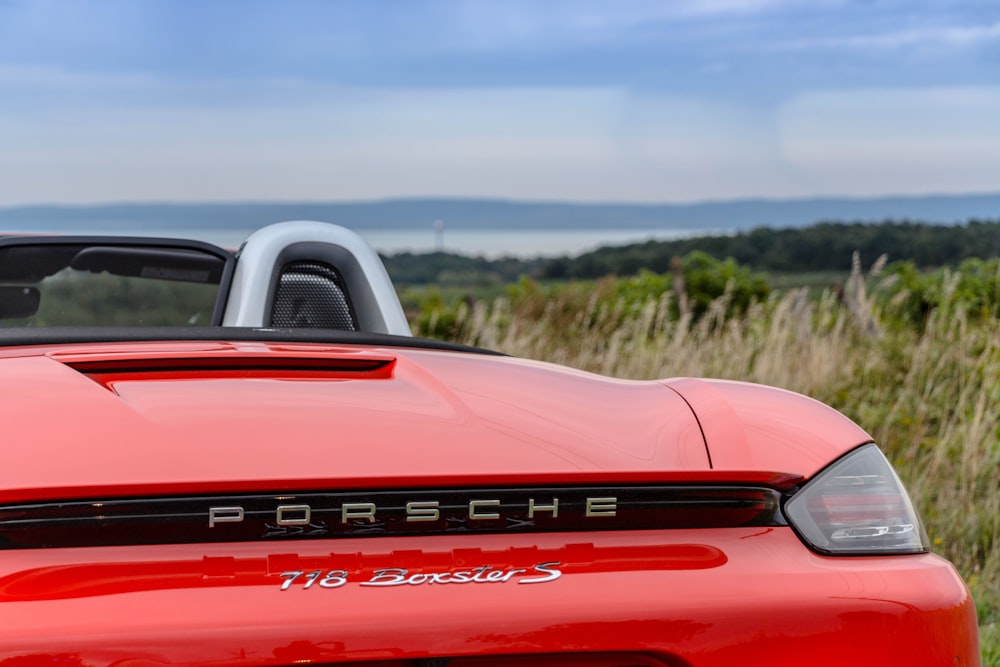 red Porsche 716 Boxster convertible coupe near green grass