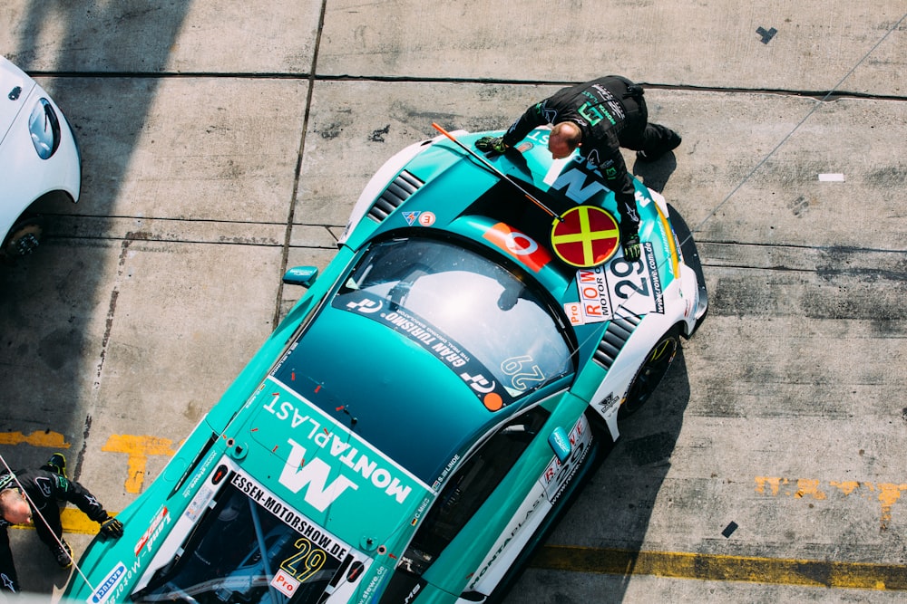 man standing in front of green and white racing car