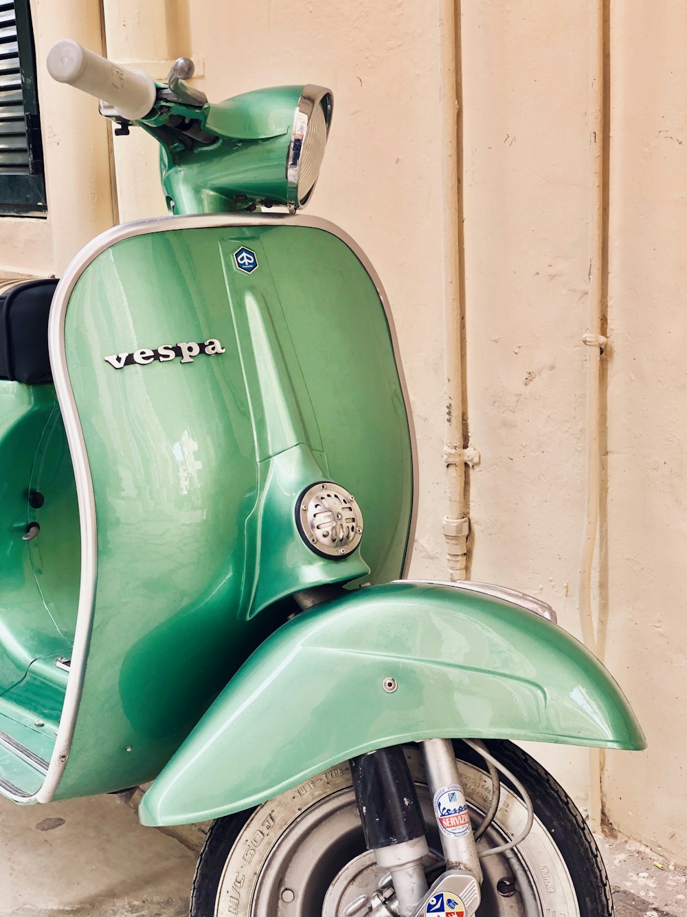 green and white Vespa motor scooter near white wall