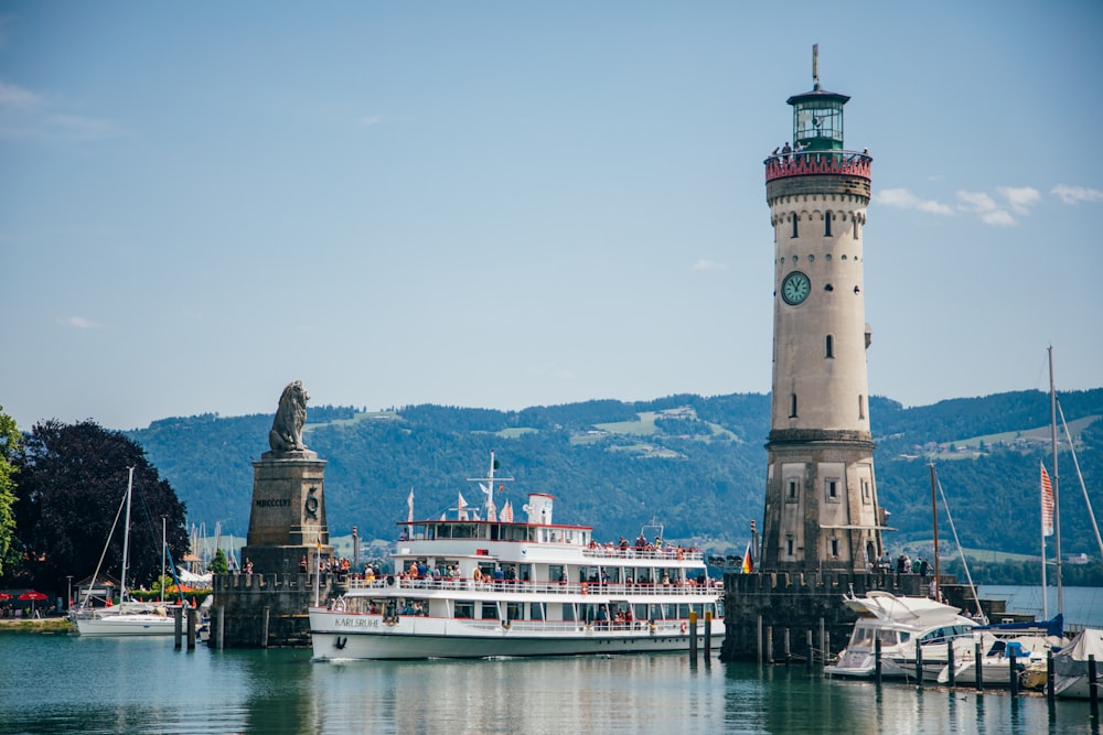 Menschen in weißem Kreuzfahrtschiff auf blauem Meer mit Blick auf den Berg unter blauem und weißem Himmel