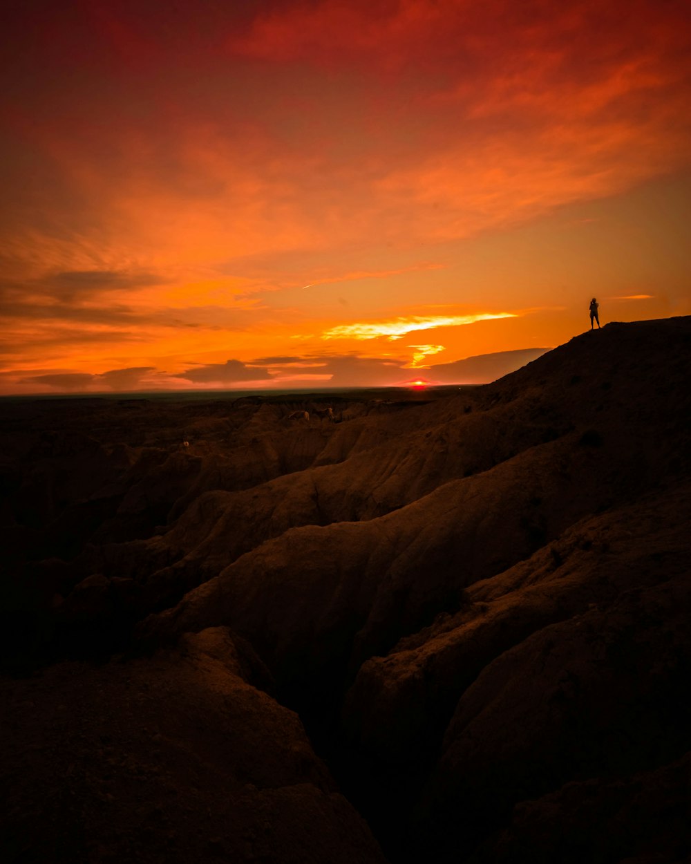 silhouette of person standing on cliff during golden hour