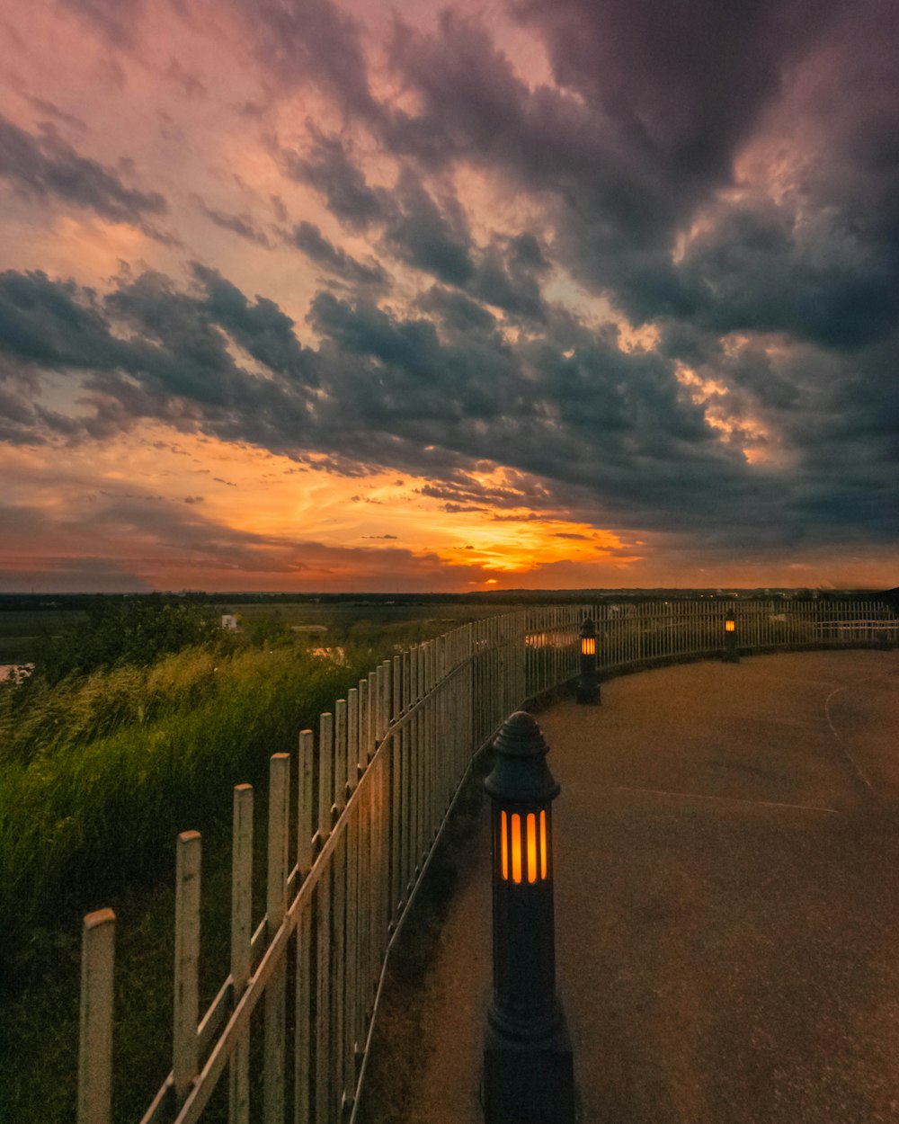 turned-on lamp posts under cloudy sky during golden hour