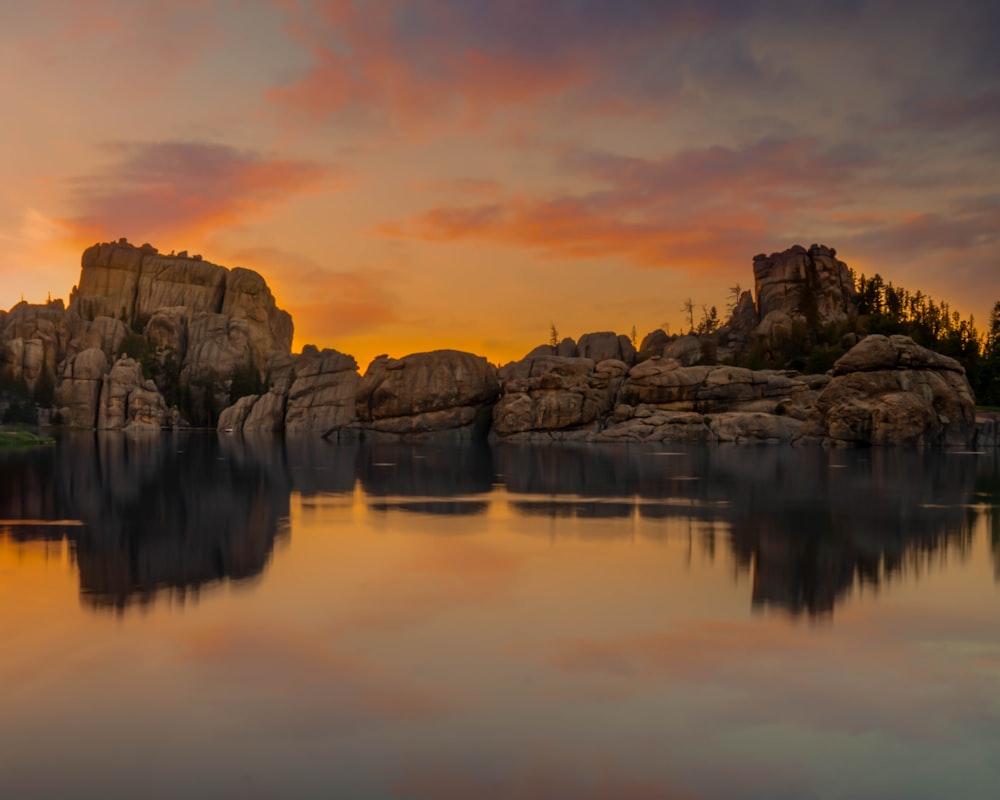 reflection of cliff on body of water during golden hour