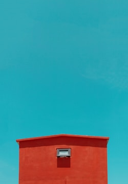 A freshly painted red and white commercial building exterior under a clear blue sky.