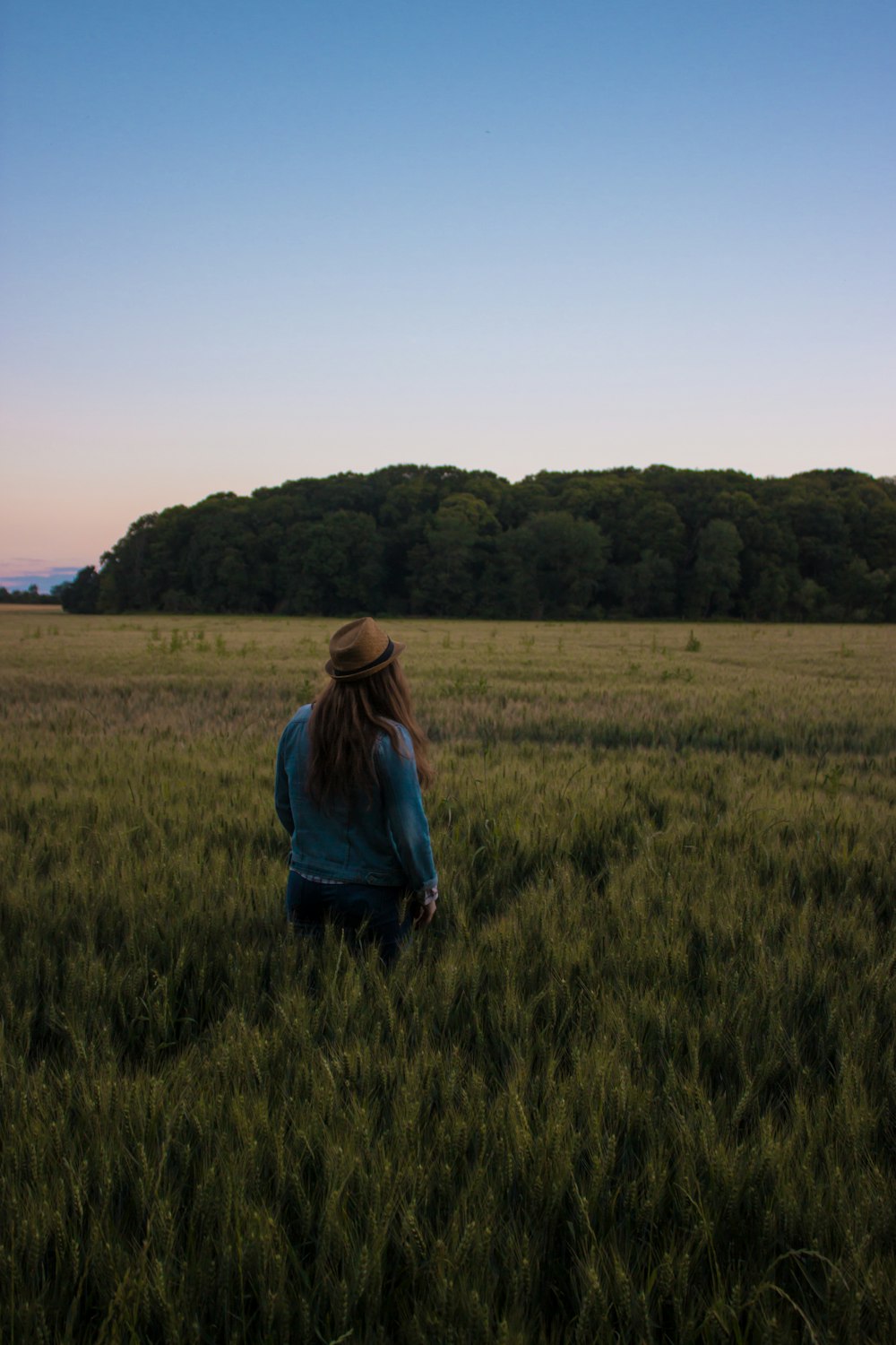 woman in blue sweater standing in middle of green grass field