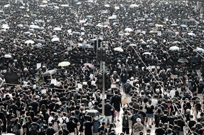 standing crowd, some using umbrellas tone google meet background