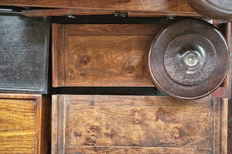 Various wooden surfaces and textures are visible, including panels and a circular object. The wood features natural grain patterns and a rich, warm tone.