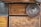 Various wooden surfaces and textures are visible, including panels and a circular object. The wood features natural grain patterns and a rich, warm tone.