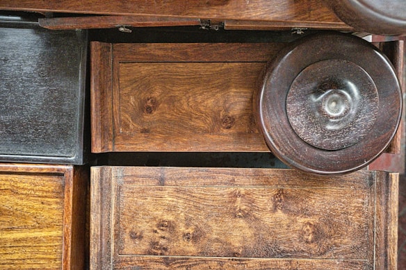 Various wooden surfaces and textures are visible, including panels and a circular object. The wood features natural grain patterns and a rich, warm tone.