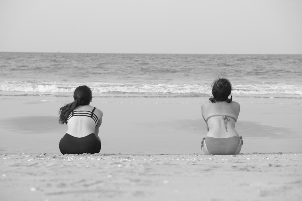 穏やかな海の海岸に座る二人の女性