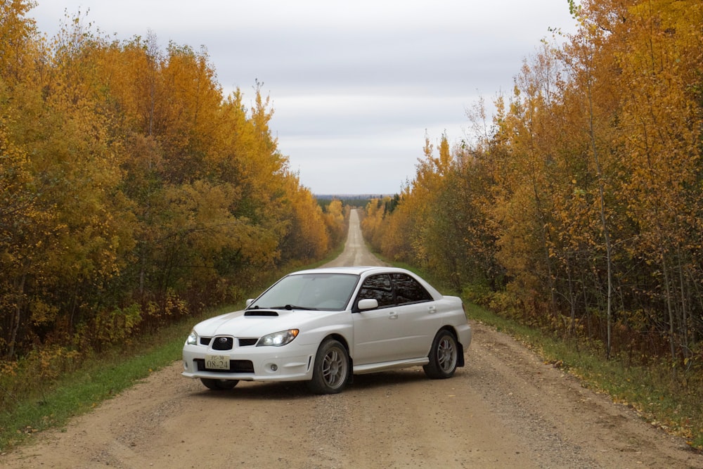 white Subaru Impreza WRX sedan parked diagonally in middle of dirt track during daytime