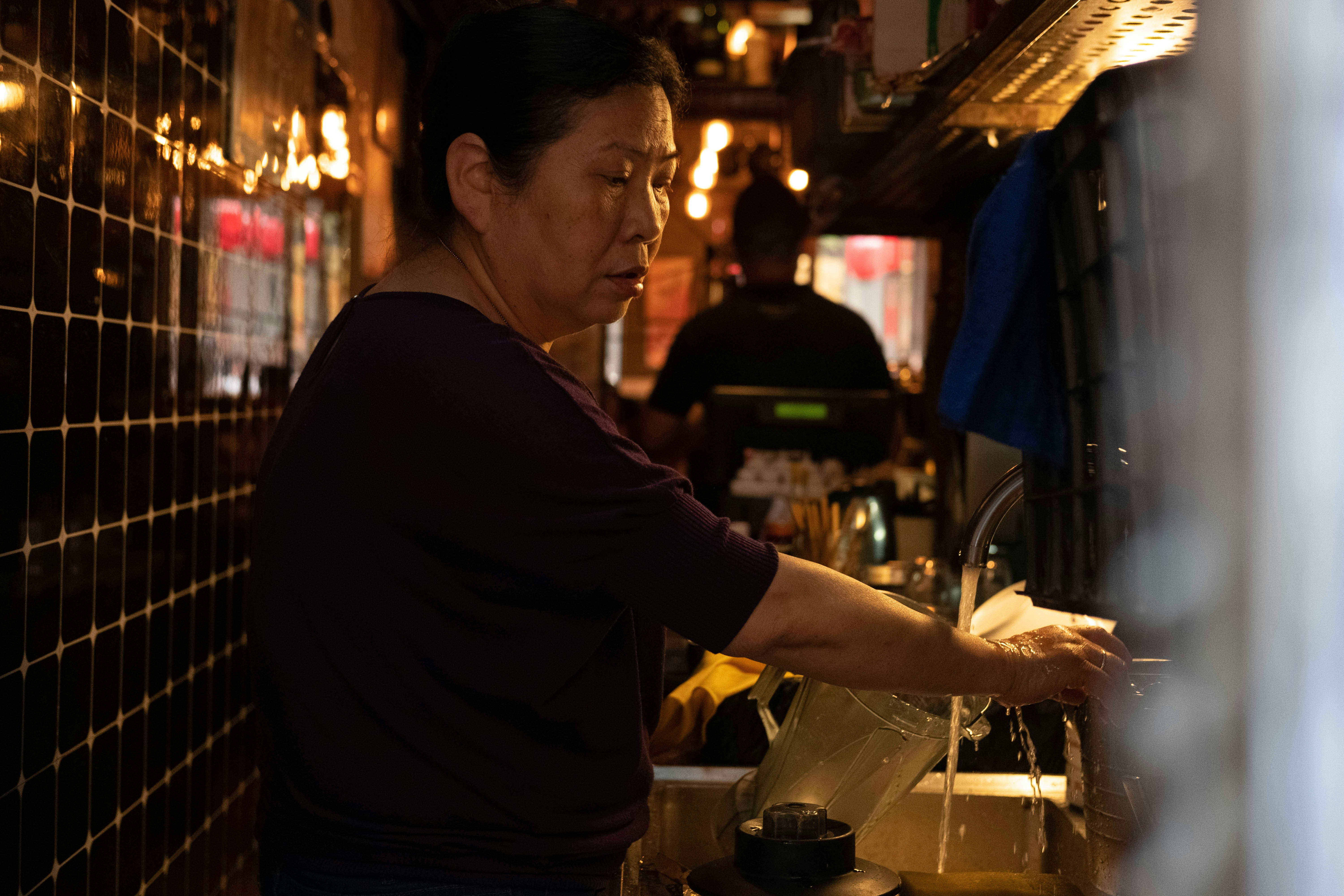 woman washing pitcher at kitchen sink