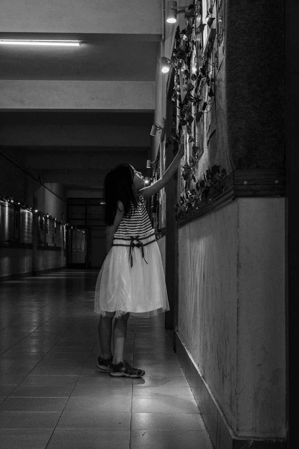 grayscale photo of girl standing by wall