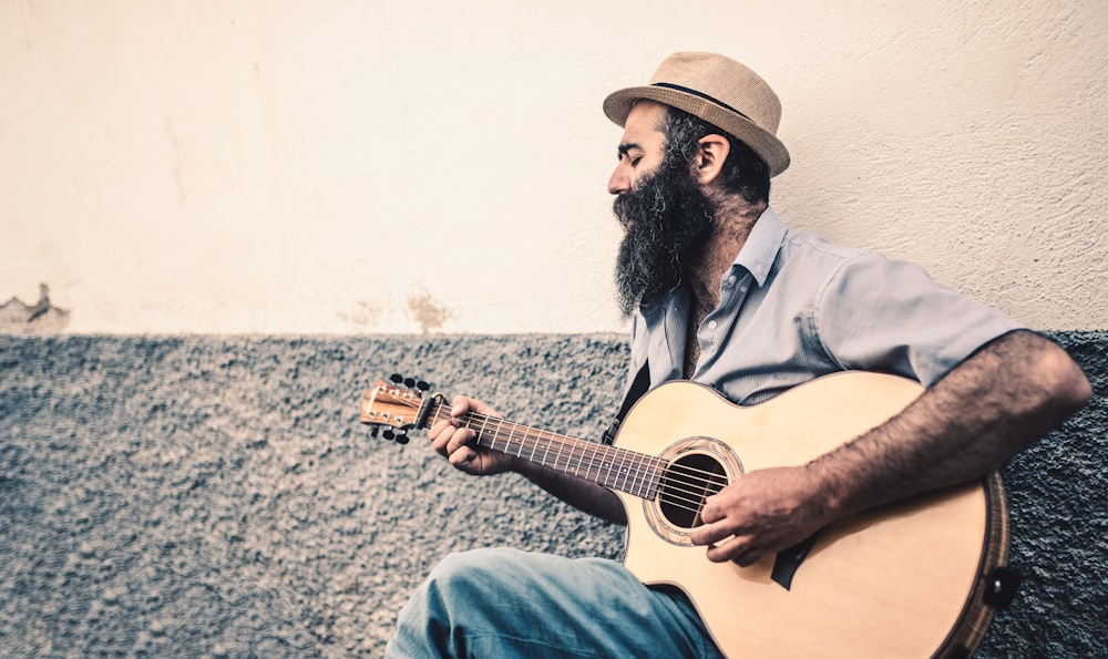 man in grey collared shirt-sleeved shirt playing guitar