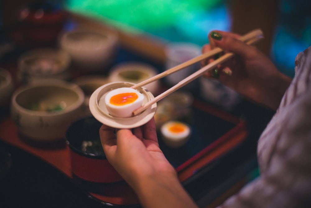 person holding chopsticks in plate