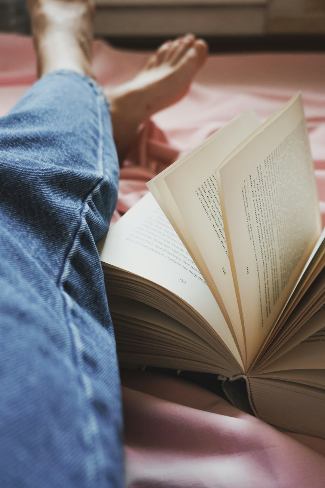 person in blue denim jeans and hard bound book on the side