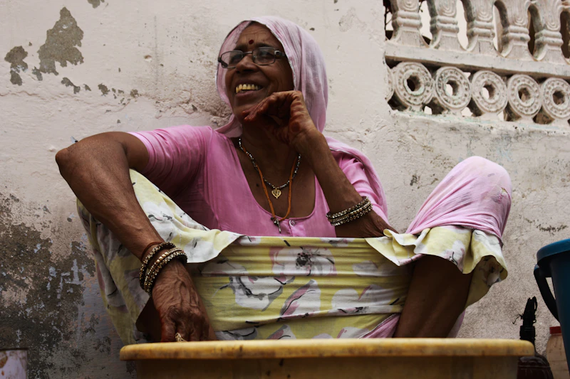 woman sitting on floor wearing pink scoop-neck shirt and hijab scarf