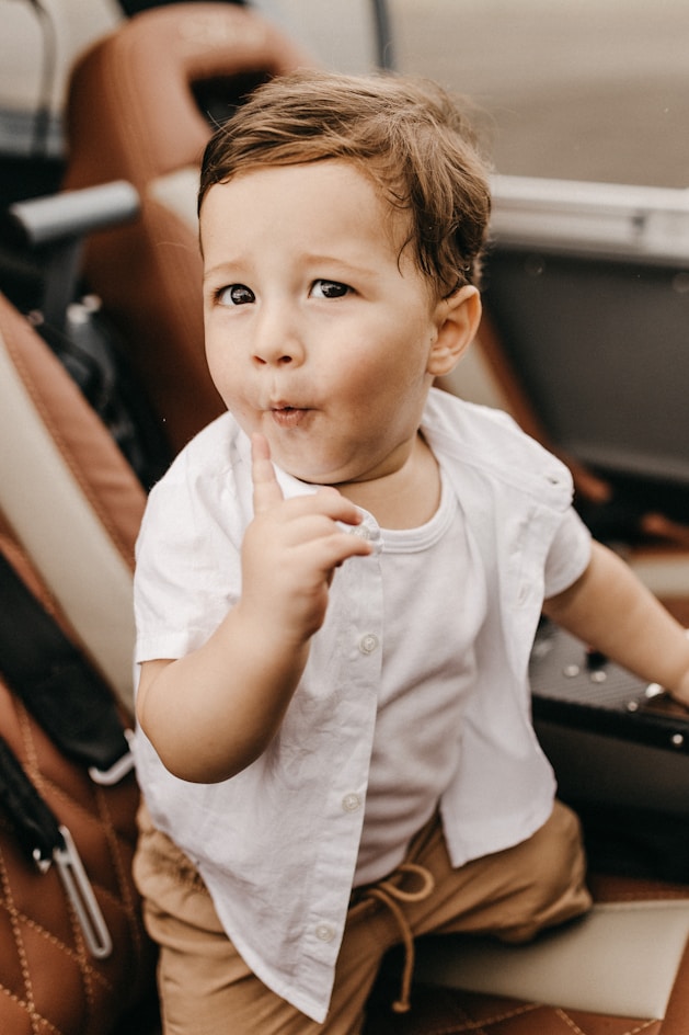 boy wearing white button-up t-shirt, white tank top and brown bottoms