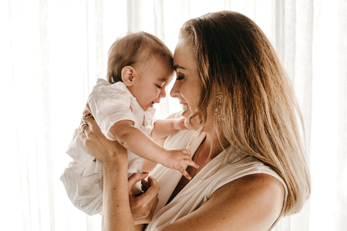 A mother holding her smiling baby in soft daylight