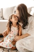 a woman sitting on the floor with a little girl