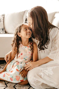 A mother and daughter sharing a laugh, both dressed in cozy, fashionable Vorzaya outfits.