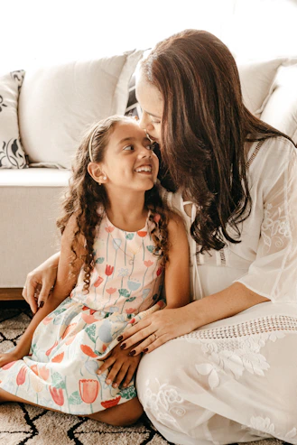 a woman sitting on the floor with a little girl