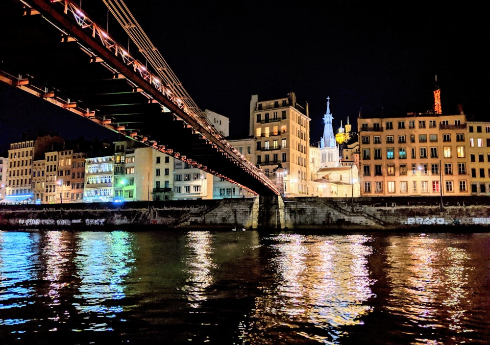 low angle photography of steel bridge near buildings at night