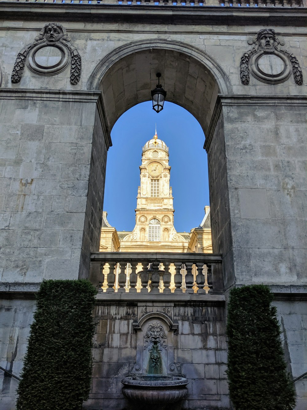 a clock tower seen through an arch in a stone building