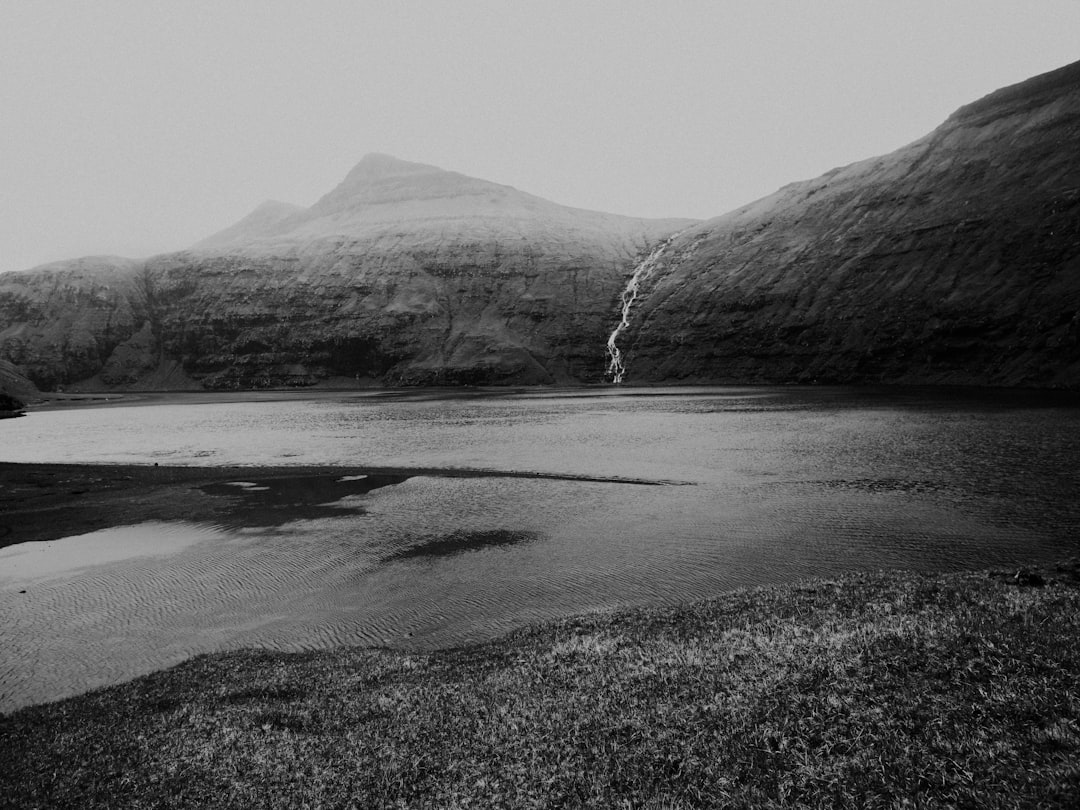 grayscale photography of lake near mountain