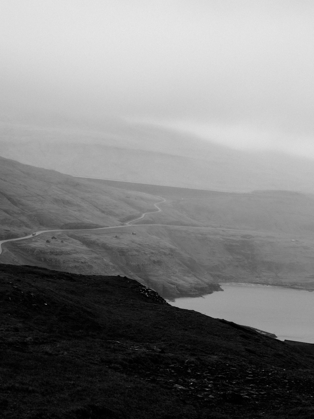 Fotografía en escala de grises de una montaña cerca del lago