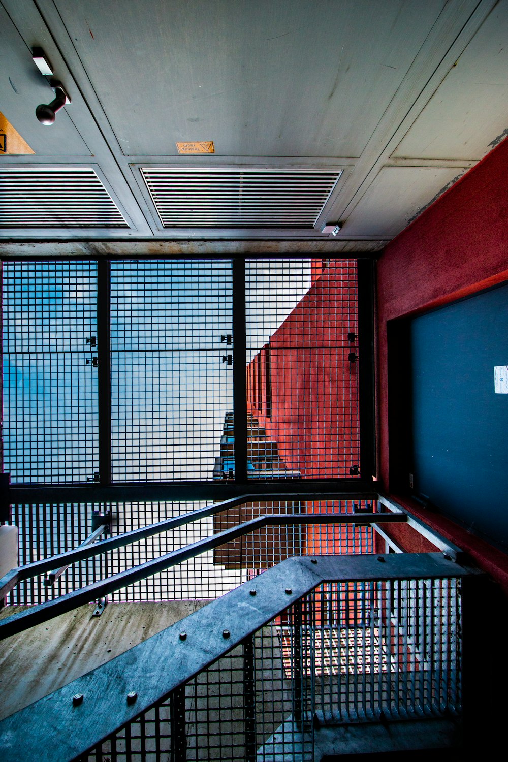 a room with a metal railing and a red wall