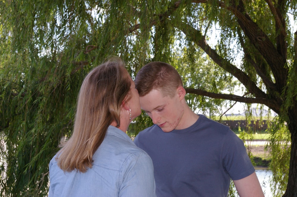 man and woman kissing under green tree