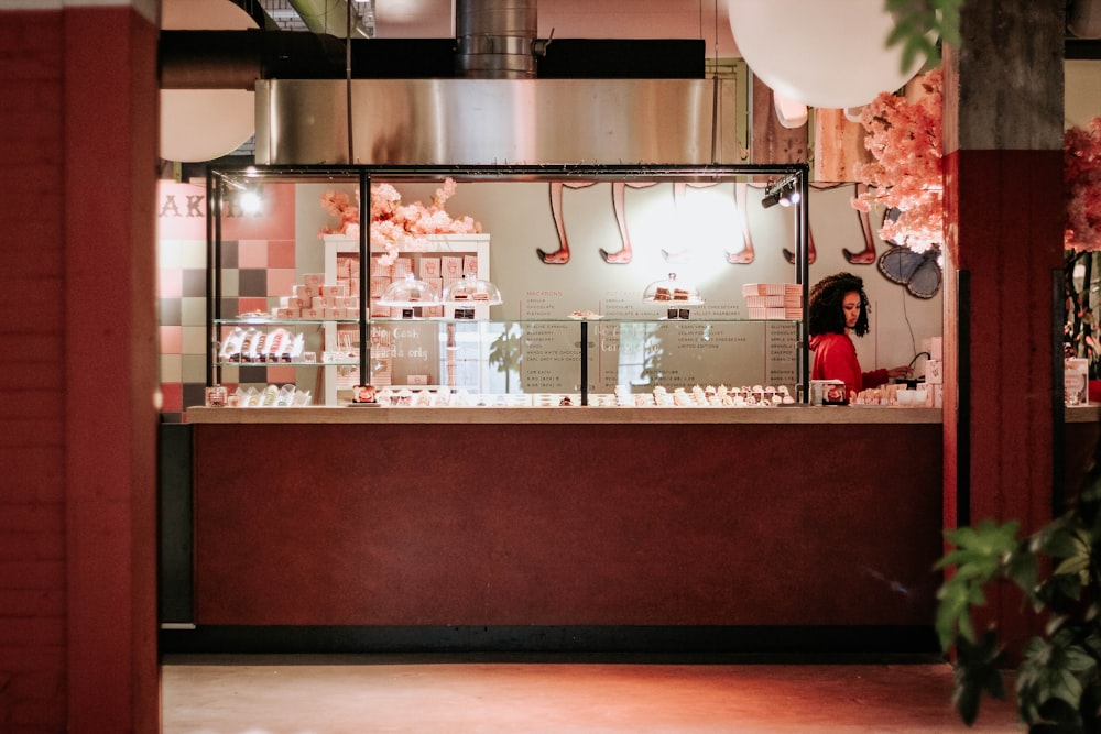 femme debout à côté d’un comptoir d’affichage en verre transparent