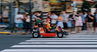man riding go cart on pedestal lane near people watching