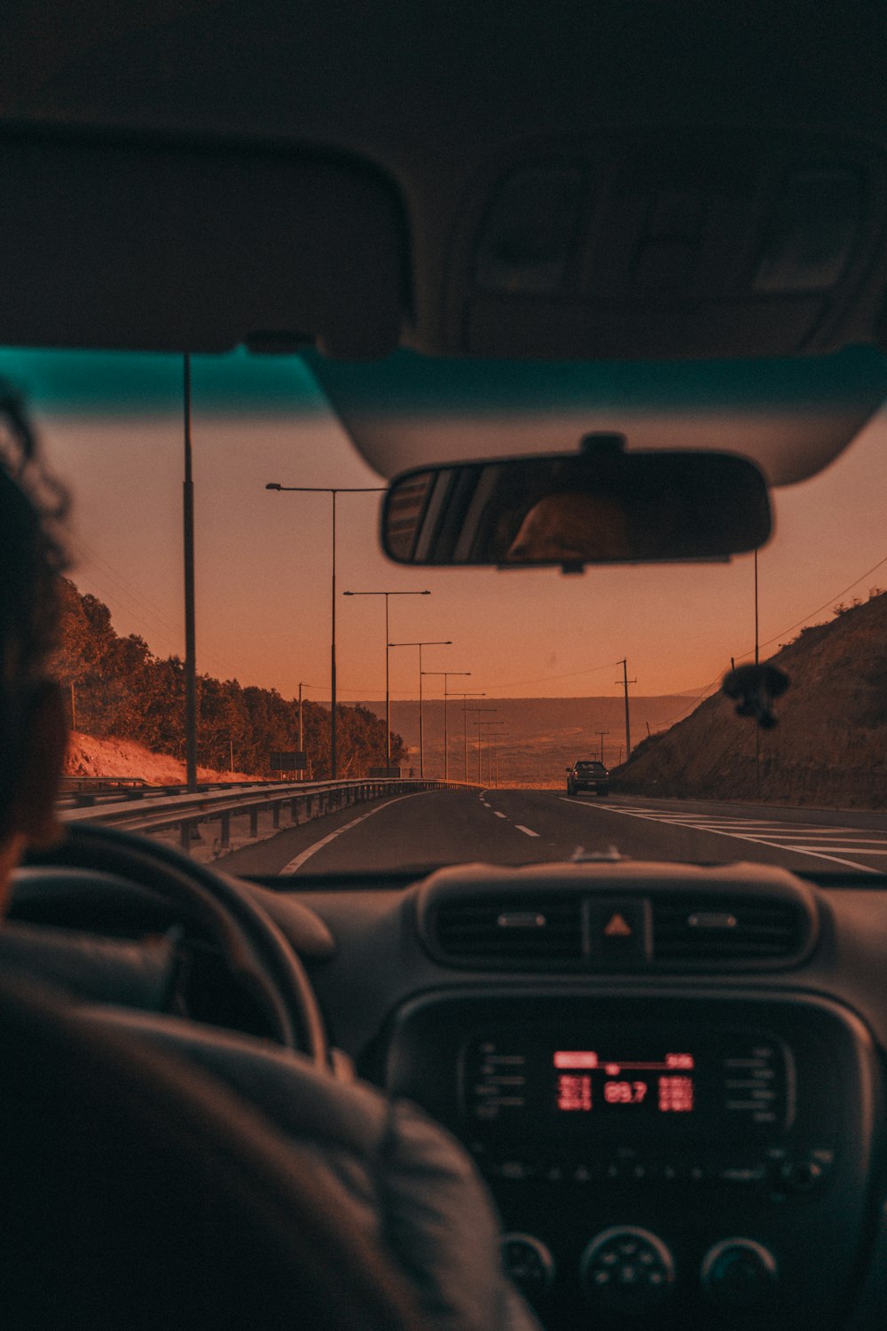a man driving a car on a highway at sunset