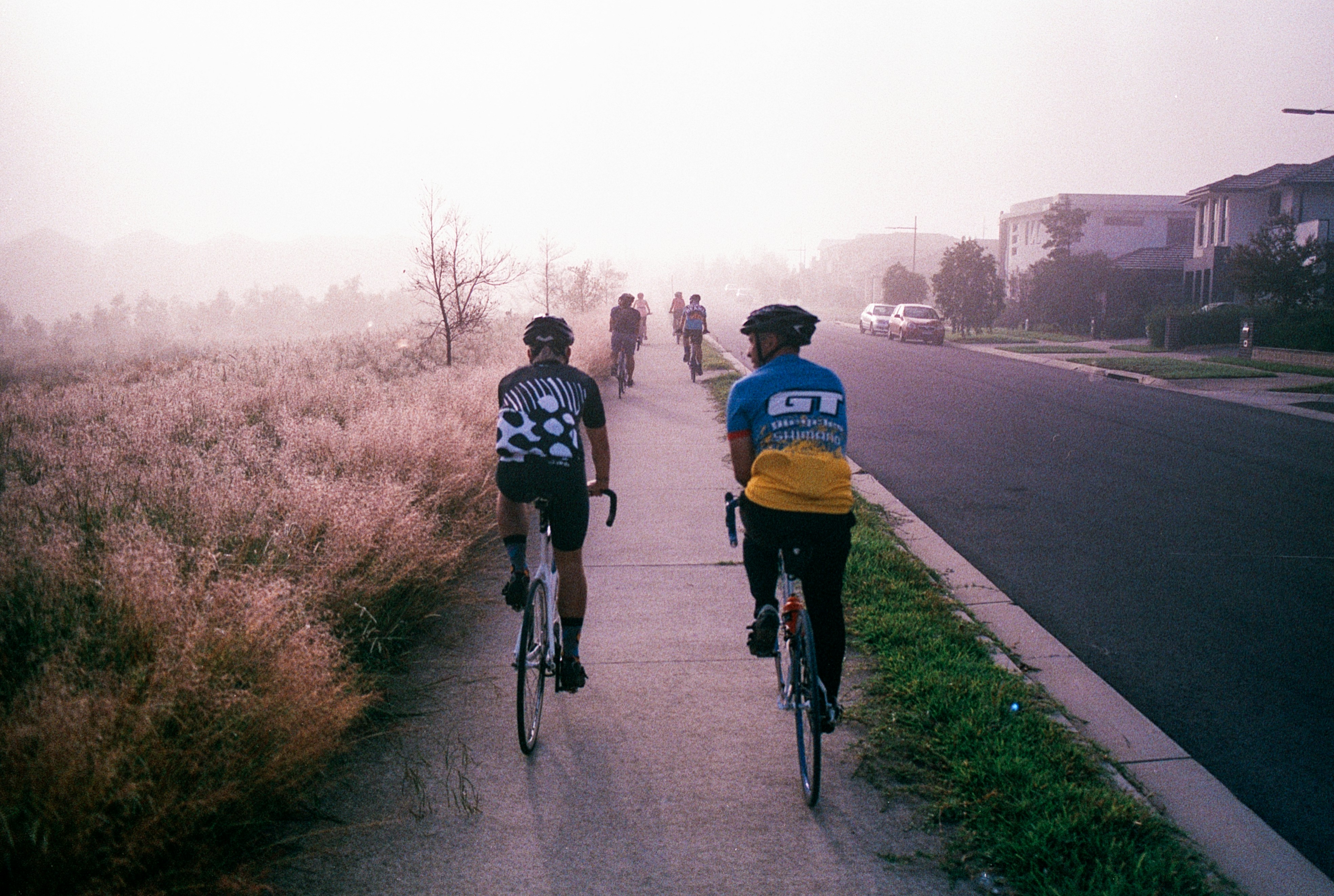 Dos ciclistas pasean en bicicleta por un sendero suburbano.