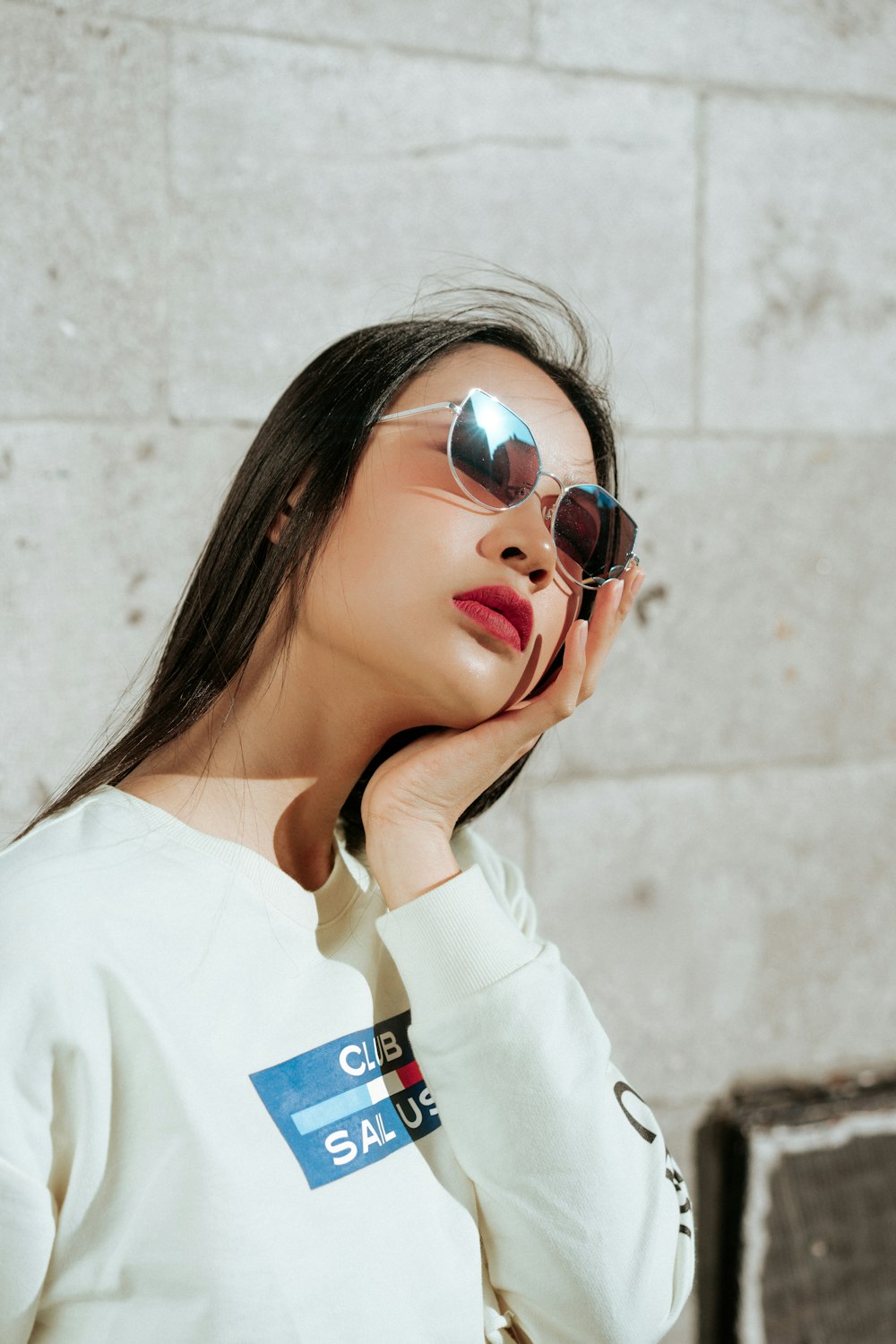 woman wearing white long-sleeved shirt holding chin