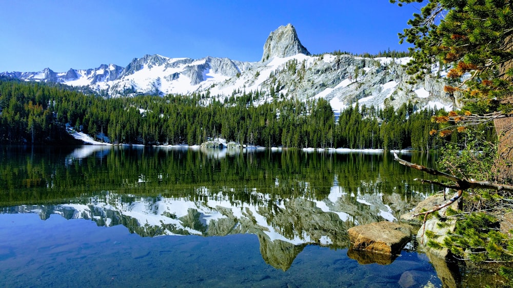 montagna coperta di neve che osserva il lago sotto i cieli blu e bianchi