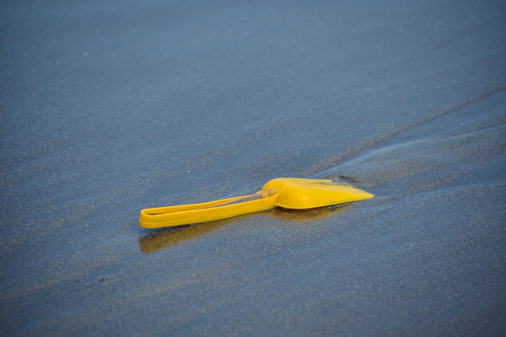yellow plastic sand shovel on gray sand