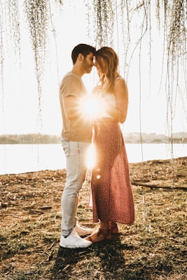 man wearing beige crew-neck shirt and white jeans holding hands with woman wearing pink dress