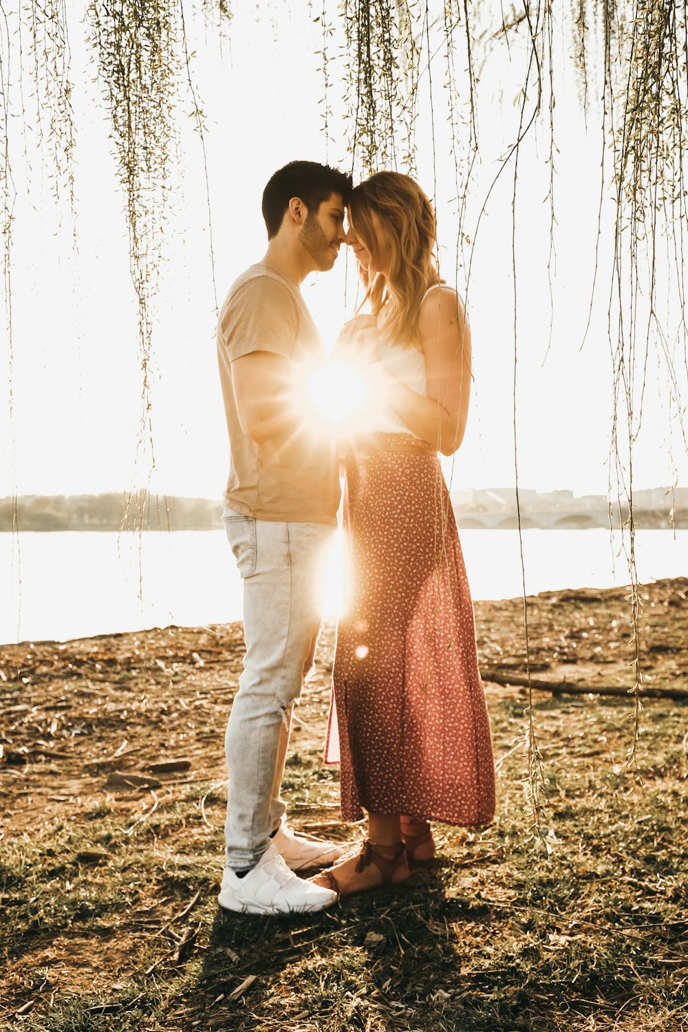 man wearing beige crew-neck shirt and white jeans holding hands with woman wearing pink dress