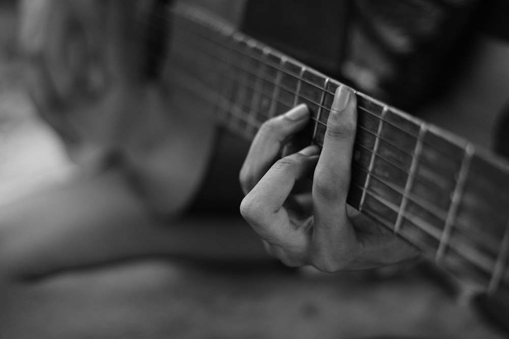 grayscale photo of a person playing acoustic guitar