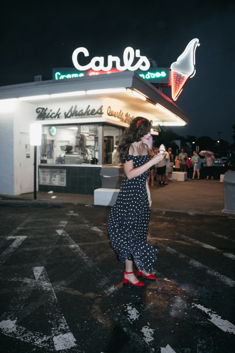 woman wearing black and white polka-dot tube dress standing near ice cream shop