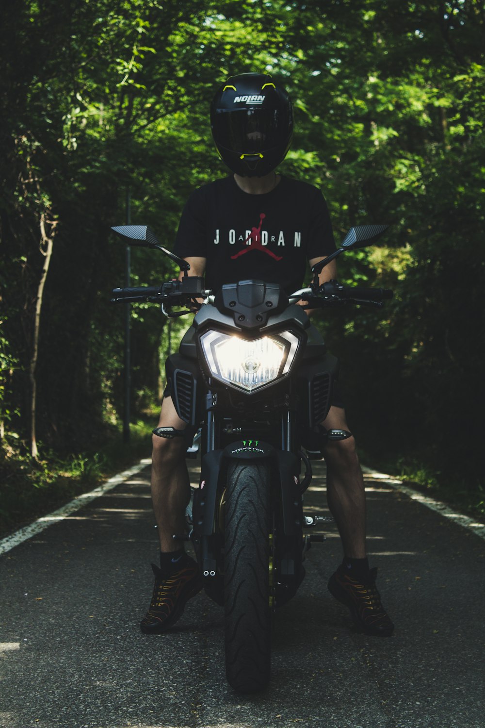 man in black Air Jordan t-shirt sitting on black motorcycle