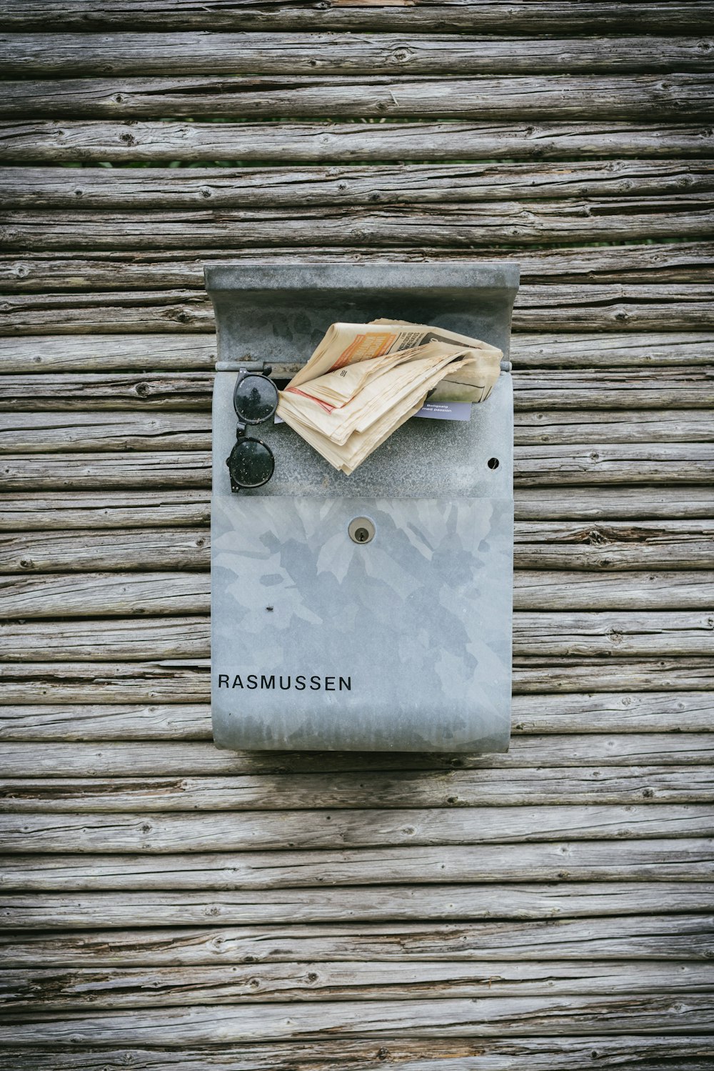 mailbox on wall with papers sticking out and black sunglasses hanging