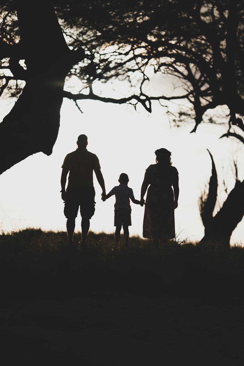 three person standing in between of two tress during daytime grey-scale photography