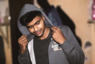 Lifestyle scene showing a confident woman smiling gently while wearing a cozy hoodie in a softly lit room.