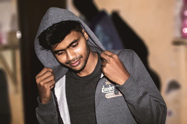 Lifestyle scene showing a confident woman smiling gently while wearing a cozy hoodie in a softly lit room.