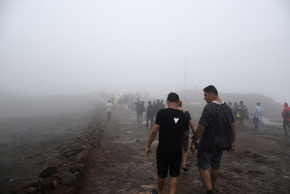 霧のかかった未舗装の道路を歩く人々