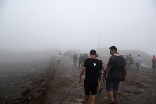 people walking on dirt road with fog in Raigad Fort India